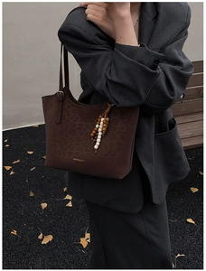 Détail du sac cabas vintage en cuir ciré avec texture léopard et gland en perles de bois