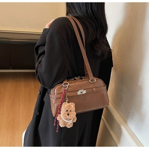 Detailed view of a vintage brown shoulder bag with a cute plush bear charm and woven cord