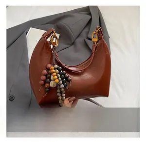 Détail du sac hobo en cuir marron vintage avec perles et garniture dorée