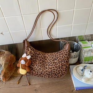 Detail of leopard print crossbody bag with brown leather strap and plush bear charm