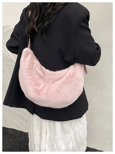 Detail of pink faux fur crescent shoulder bag with leather strap on a model's shoulder