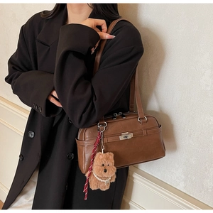 Detail of vintage dark brown faux leather bag with silver lock and plush dog charm