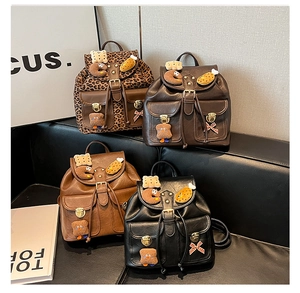 Retro mini backpacks in leopard print, brown, and black with cute plush charms on a sofa