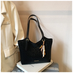 Détail du sac cabas noir à motif léopard avec breloque en perles et poignée réglable