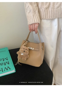 Detailed close-up of khaki litchi grain bucket bag featuring a silver twist lock and charm