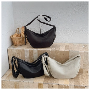 Minimalist hobo bags in dark brown, black, and cream white on a stone steps display