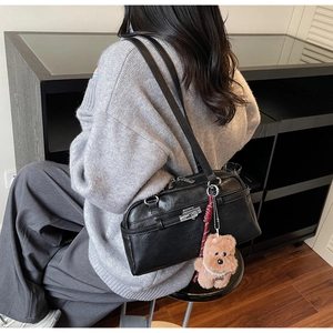 Detail of black leather Boston bag featuring a plush bear charm and silver-tone hardware