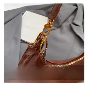 Détails de l'attache métallique dorée et du cuir marron foncé du sac à bandoulière