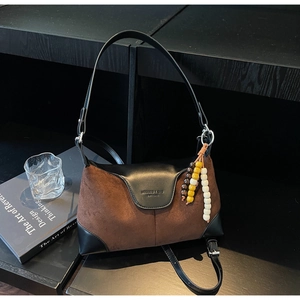 Detail of vintage suede shoulder bag with leather flap and decorative bead charm