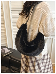 Lifestyle shot of a black faux fur hobo bag with leather strap on a model's shoulder