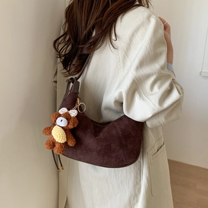 Detail of dark brown faux suede crescent bag featuring a cute plush bear charm accessory