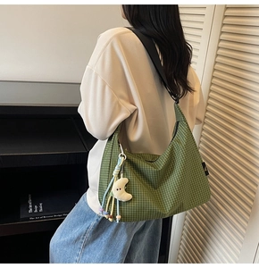 Détail du sac hobo en toile à carreaux verts avec bandoulière et breloque lune en peluche