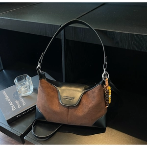 Detail of suede and leather patchwork bag with bead charm and engraved MIKAURA logo