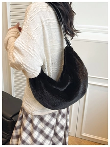 Detail view of the black plush crescent bag worn over the shoulder with soft fabric texture
