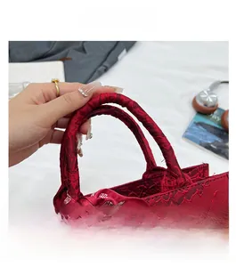Détail du sac de mariée rouge avec broderie florale et foulard de mariage au manche