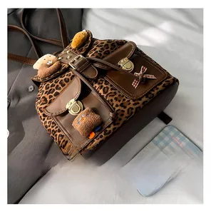 Detail view of leopard print backpack with brown leather accents and gold metal buckles