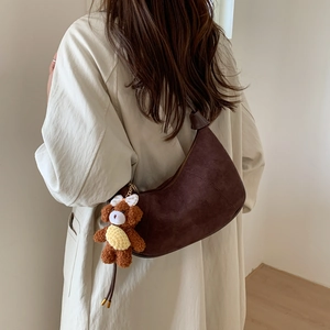 Detail of a dark brown suede hobo bag featuring a cute teddy bear charm on the strap