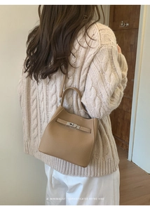 Detailed close-up of beige lychee grain leather handbag with vintage metal clasp