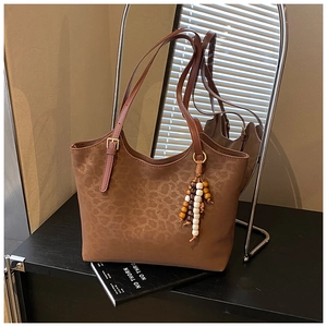 Détail d'un sac cabas léopard avec pendentif en perles de bois et bandoulière réglable