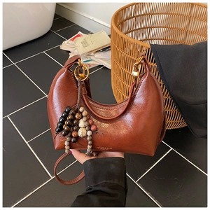 Détail du sac hobo marron avec finition brillante et décoration en perles de bois