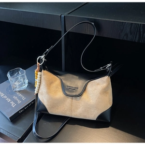 Close-up of contrast beige suede shoulder bag with beaded charm and brand logo