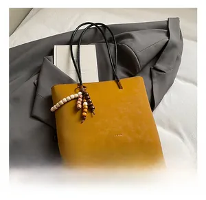 Dettaglio della borsa tote color zenzero opaco con manici neri e nappa in legno