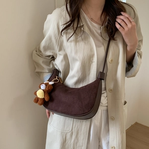 Detail of dark brown hobo shoulder bag with plush bear charm and suede texture