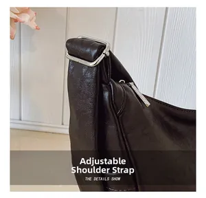 Detail of adjustable shoulder strap and silver hardware on black pebble leather bag
