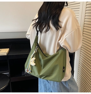 Détail du sac hobo en toile à carreaux verts avec étiquette noire et breloque lune
