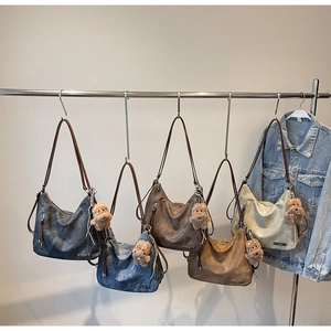 Detail of soft leather tote bags in five vintage colors with cute bear charms on a rack