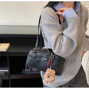 Detail of black Boston shoulder bag featuring a cute brown plush bear charm accessory