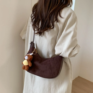 Detail of dark brown faux suede hobo bag with a cute teddy bear charm on shoulder