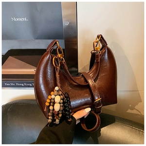 Détail du sac à main demi-lune en cuir marron foncé avec breloque en perles de bois colorées