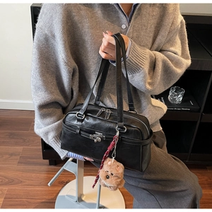 Detail of black matte leather shoulder bag with silver turn-lock and plush charm