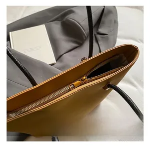 Dettaglio della cerniera dorata e del manico nero sulla borsa tote in ecopelle marrone chiaro