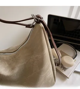 Detail of khaki canvas bag with brown leather strap and metal buckle adjustment