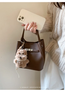 Detail of dark brown leather bucket bag with silver buckle and plush dog charm