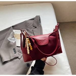 Detail of burgundy leather dumpling bag with gold logo, suede panel and colorful wood beads