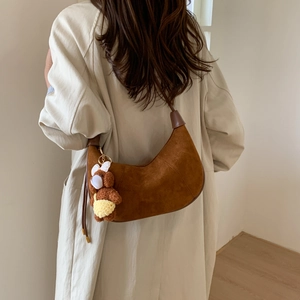 Detail view of brown suede hobo bag worn by model over a stylish beige long coat