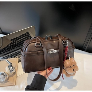 Close-up of brown faux leather Boston bag featuring silver metal buckle and dog charm