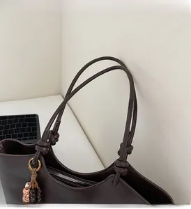 Detail of vintage brown leather handbag with knotted handles and beaded charm