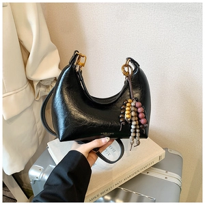 Détail du sac hobo en cuir noir avec boucles dorées et pendentif en perles colorées