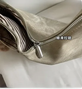 Detail of smooth silver zipper with striped lining and brown plush charm on the tote bag