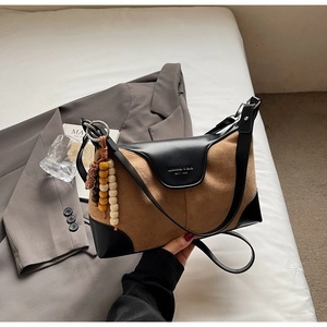 Detail of brown suede crossbody bag with decorative wooden beads on white bedding