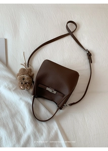 Detail of dark brown pebble leather bucket bag with silver lock and plush bear charm