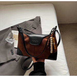 Detail of vintage patchwork tote bag with brown suede, black leather and wood bead charm