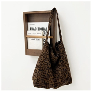 Detail view of large leopard print tote bag hanging on a minimalist wooden wall rack