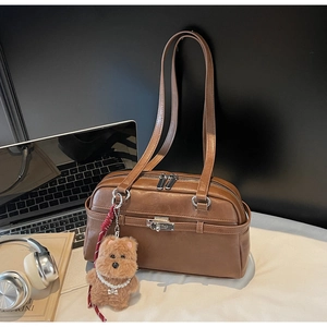 Detail view of a vintage brown leather Boston bag featuring a cute plush bear pendant