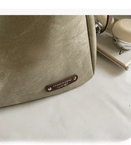 Detail shot of khaki canvas fabric texture with brown leather logo patch and silver studs