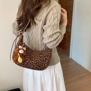 Leopard print crescent shoulder bag featuring a cute brown plush bear charm detail